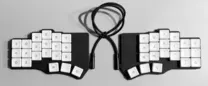Teclado dividido blanco y negro sobre una superficie clara.