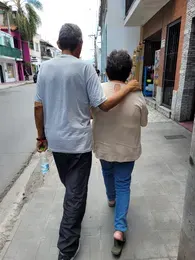 Dos personas caminando de espaldas por una vereda.
